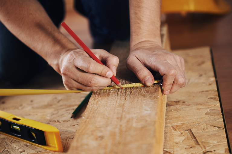 A workman measuring a wooden plank