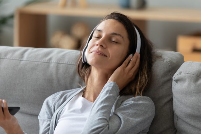 A woman wearing headphones as she sits on a sofa