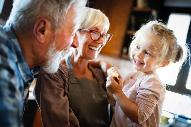 Happy smiling grandparents enjoying time with grandchild at home